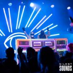 DJ BOOTH, LIGHTING & HOLOGRAMS (5) DJs playing music with the DJ booth at an event at night