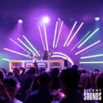 DJ Booths, Holograms & Lighting (1) DJ hosts using the DJ booth for a party event with a crowd dancing behind them nighttime