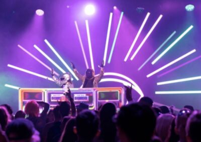 DJ Booths, Holograms & Lighting (1) DJ hosts using the DJ booth for a party event with a crowd dancing behind them nighttime