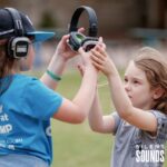 SILENT DISCO FOR SCHOOLS AND OSHC HIRE (1) Two school children holding and wearing Silent Sounds Headphones outside