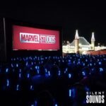 SILENT CINEMA HIRE (1) A group of people watching a cinema movie outside at night wearing LED Silent Sounds Headphones