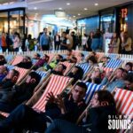 SILENT CINEMA HIRE (4) A group of people sitting down watching a movie wearing Silent Sounds Headphones in a shopping centre