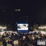 SILENT CINEMA HIRE (3) A group of people watching a cinema movie outside at night LED wearing Silent Sounds Headphones