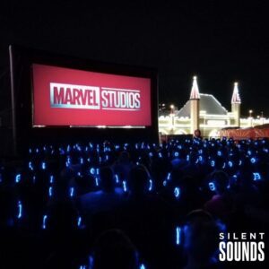 SILENT CINEMA HIRE (1) A group of people watching a cinema movie outside at night wearing LED Silent Sounds Headphones