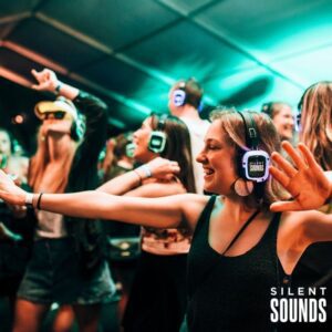 SILENT DISCO HIRE (5) A group of happy teenagers dancing at a disco (nighttime) wearing LED Silent Sounds Headphones.