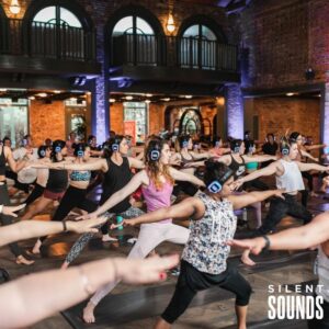 SILENT YOGA & FITNESS HIRE (1) A Yoga event with a group of people wearing Silent Sounds Headphones inside.