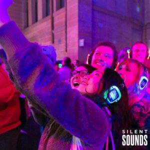 SILENT WALKING TOUR HIRE (4) A group of people taking a selfie at night outdoors wearing LED Silent Sounds Headphones.